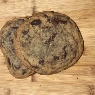 two chocolate chip cookies on a cutting board