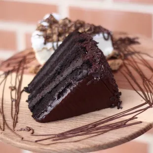 a slice of chocolate cake on a wooden plate