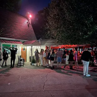 a group of people standing outside of a restaurant at night