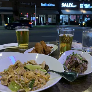 Pad Thai, fried chicken wings with sweet chili sauce, and Thai beef salad. Singha Beer