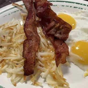Hash browns, bacon and two eggs sunny side up.