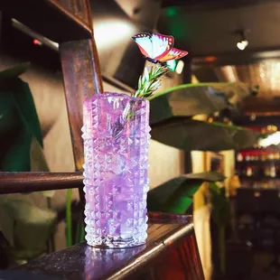 a purple glass with a flower in it