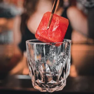 a watermelon on a stick in a wine glass