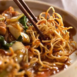 a bowl of noodles with chopsticks