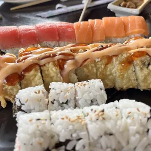 a variety of sushi on a black plate