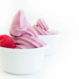 ows two bowls of yogurt with raspberries