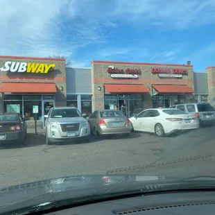cars parked in front of a subway restaurant