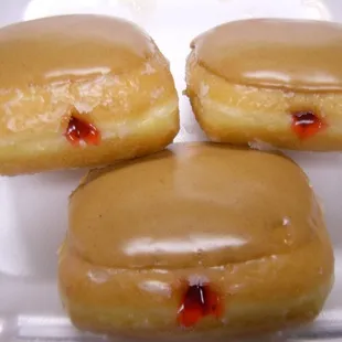 three glazed donuts in a styrofoam container