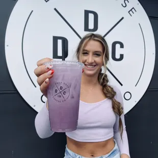 a woman holding a purple drink