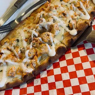 a cheesy pizza on a red and white checkered table cloth