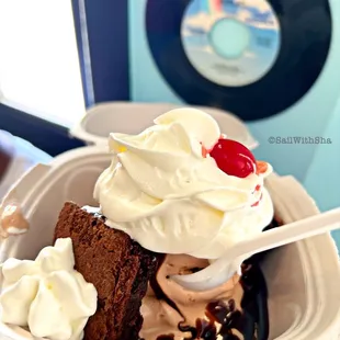 a hand holding a bowl of ice cream and a piece of cake