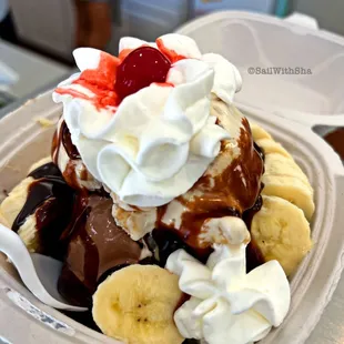 a banana split sundae with whipped cream, strawberries, and chocolate