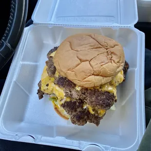 a cheeseburger in a styrofoam container