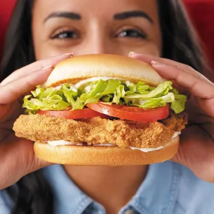 a woman holding a sandwich in front of her face