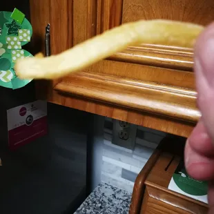 a hand holding a piece of food in front of a refrigerator