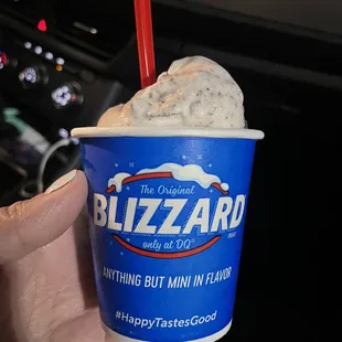 a hand holding a cup of blizzard ice cream