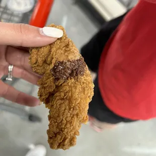 a hand holding a half eaten fried chicken