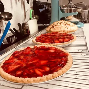 two strawberry pies on a cooling rack