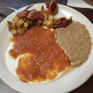 Huevos Rancheros, pan fried potatoes , and refried beans.