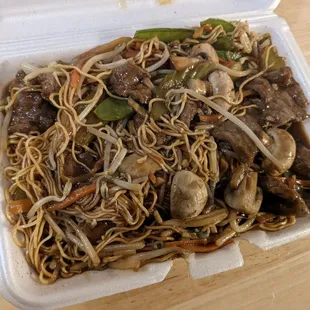 a take out container with noodles and meat
