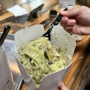 a hand holding a fork and a container of food