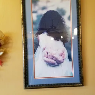 A picture on the wall of a woman in a wedding dress carrying a bag of bread.