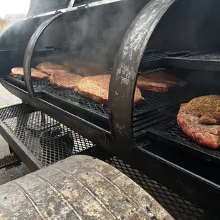 a grill with steaks cooking on it