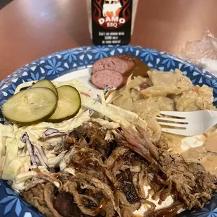 a plate of pulled pork, coleslaw, coleslaw, and pickles