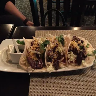 three tacos on a plate with sauce