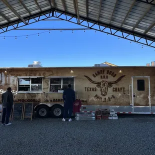 two people standing in front of a food truck