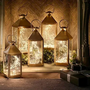 three lighted lanterns in front of a fireplace