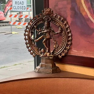 a close up of a statue in front of a road closed sign