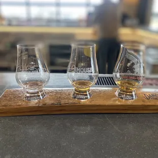 three glasses of whiskey on a wooden tray