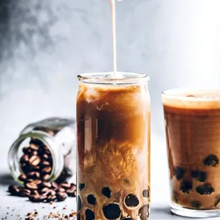 a person pouring a cup of iced coffee