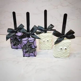 three candy apples decorated with spider webs
