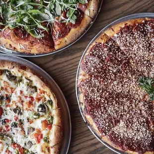 three different pizzas on a table