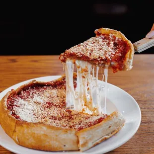 a slice of deep dish pizza being lifted by a fork