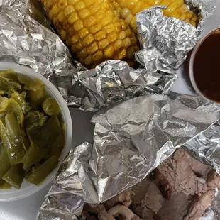 ows a plate of meat, corn, and vegetables