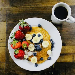 a plate of pancakes with bananas and strawberries