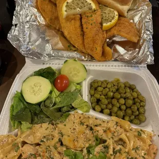 Fried fish with shrimp pasta, green peas, side salad and a dinner roll.