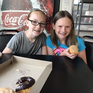 two children sitting at a table with donuts