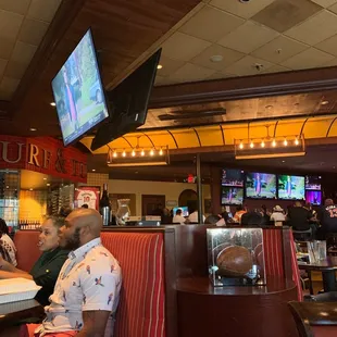 a man sitting in a booth watching tv