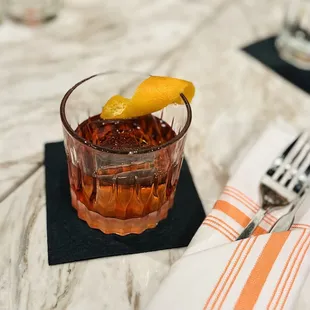 a drink in a glass with an orange garnish