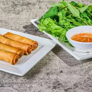 a plate of spring rolls and a bowl of dipping sauce