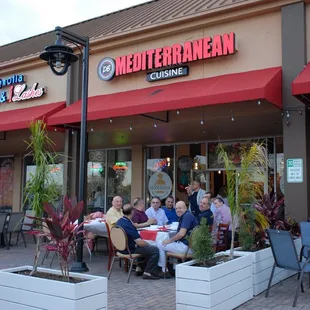 a group of people sitting outside of a restaurant