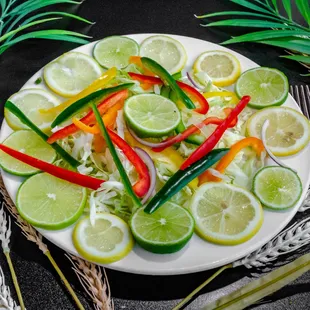 a white plate with sliced limes, peppers, and peppers