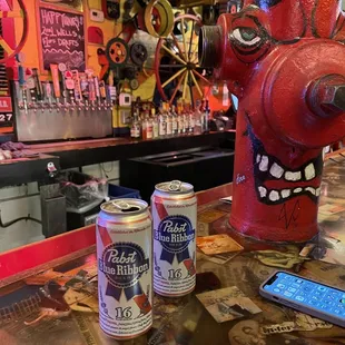 a red fire hydrant and two cans of beer