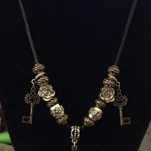 Old-fashioned looking key locket with various metal beads and small key pendants on Black suede rope necklace