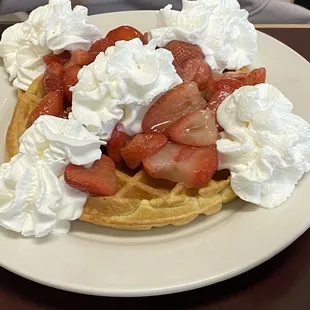 a waffle with strawberries and whipped cream
