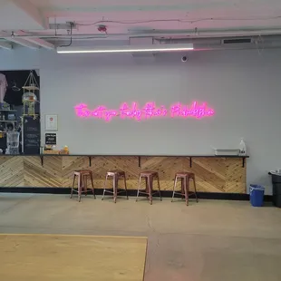 a pink neon sign in front of a bar